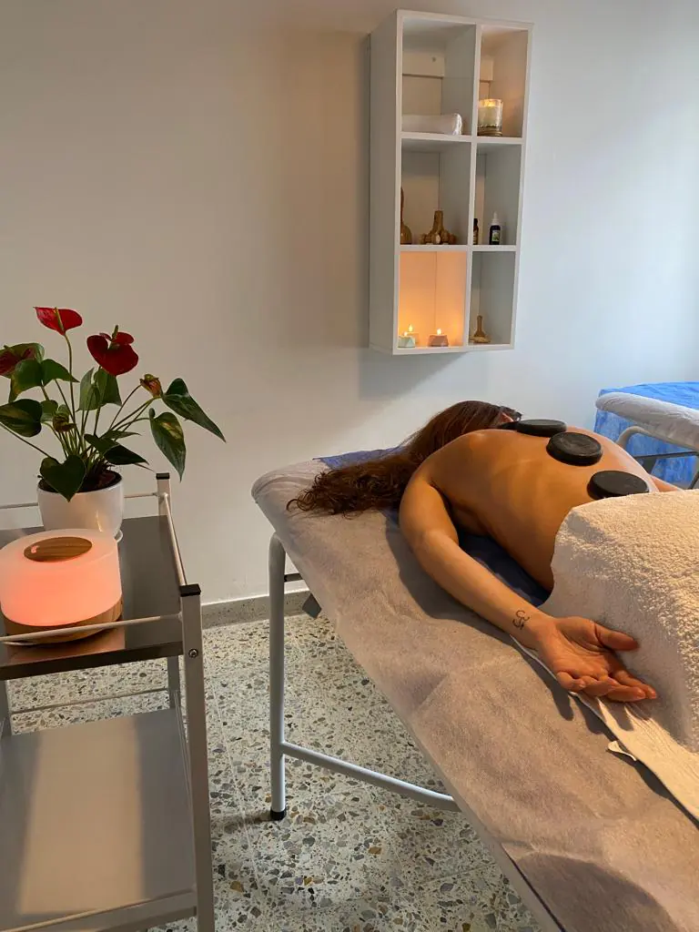 Cabina con camilla, piedras calientes y flores
